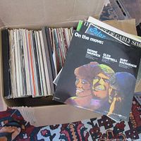 Photo of box packed with numerous LP vinyl records, front record is 'On the Move' featuring Dionne Warwick, Glen Campbell, Burt Bacharach.