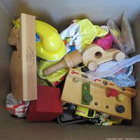 Top view of box with assorted vintage toys including wooden toys and toys in plastic bags