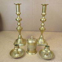 Full set of two tall candlesticks, two smaller chamberstick candle holders, and one lidded container on flat surface.