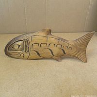 Side view of carved wooden fish showing full profile, carved details, and natural finish.