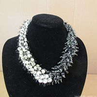 Full view of black and white beaded necklace on black bust display