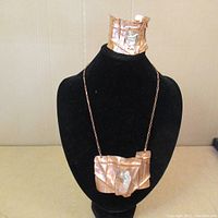 Copper necklace and matching bracelet displayed on black velvet stand, showing front and shape of both items.