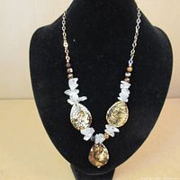 Front view of the necklace displayed on a black bust, showing three jasper stone pendants with quartz chips and small brown beads on sterling silver chain.