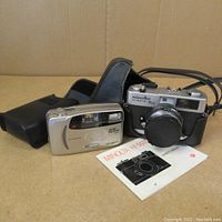 Full view of Minolta Hi-Matic 7SII camera with leather case, instruction manual, and Minolta AF50 Big Finder Date camera.