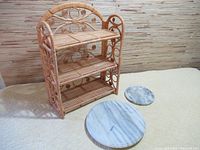 Three-tier rattan foldable shell shelf next to round marble coaster and similar larger marble lazy Susan on textured surface