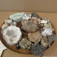 Tray view of assorted mineral specimens including geode, metallic sulfide cluster and assorted rough stones.