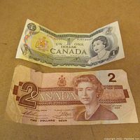 Front view of two Canada paper money bills, $1 on top and $2 below, showing front portraits and denomination details.