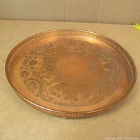 Top view of vintage copper tray showing etched floral and scroll design, pierced rim decorative border.