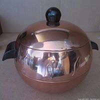 Overall front view of vintage copper ice bucket with dome lid and penguin embossing