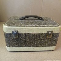 Closed view of vintage sewing box exterior showing brown and cream textured pattern and brown handle.