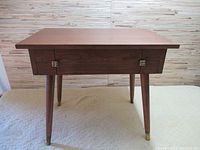 Full front view of the vintage brown wood side table with tapered legs and rectangular top.