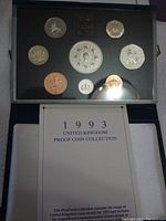 Photo of the complete 1993 UK Proof Coin Collection displayed in the original protective foam case, showcasing nine coins of various denominations including the special 5 pound Crown. Booklet titled '1993 United Kingdom Proof Coin Collection' is partially visible below the display case.