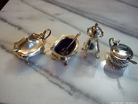 Photo of all four items together on a marble surface showing the three salters with blue liners and spoons plus one salt shaker.