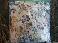 Photo of large zip-lock bag filled with many cut-out used postage stamps mostly from Canada with various designs and cancellation marks.