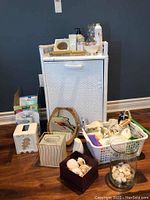 Overall view of the white wicker bedside table with items arranged on and around it on the floor.