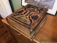 Full view of Bible closed showing decorative embossed leather cover with gold accents and wear.