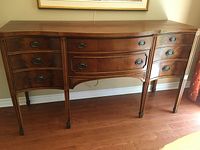 Front view of entire wood buffet sideboard with serpentine front and oval handles.