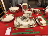 Overall layout showing dinner plates, salad plates, mugs, bowls, and serving items on red tablecloth