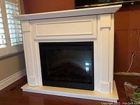 Front view of white console with black framed glass electric fireplace insert