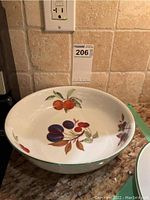Oval serving bowl with fruit and leaf pattern inside and on side.