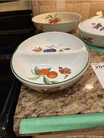 Photo showing the front view of the divided serving dish with orange and plum fruit decorations on a kitchen counter.