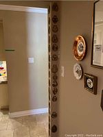 Photo showing multiple horse brasses hung vertically on a corner wall ranging in size and design.