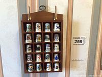 Front view of wooden display shelf with 20 porcelain souvenir thimbles