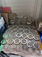 Top down and angled views of 30 assorted glass canning jars with metal lids, arranged on a towel.