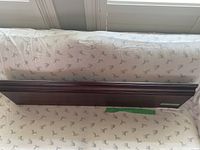 Wood floating shelf in dark brown finish lying on fabric-covered surface.