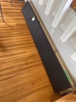 Two black floating shelves stacked on the floor, one still in original packaging, showing length and finish.