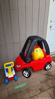 Red and black Fisher Price rolling car with yellow horse head and a walk-behind cart with yellow handle.