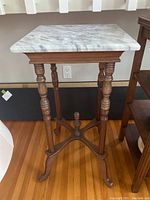 Front view of square marble top table with turned wooden legs and cross stretcher base