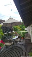 Full patio set on balcony with six chairs, glass-top table, and umbrella in open position