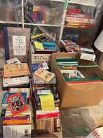 Boxes and stacks of assorted books including fiction, cookbooks, gardening and others wrapped partially in plastic