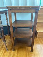 Front and side view of the wooden vintage telephone stand showing its three shelves and structural design.