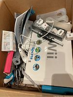 Top view of box holding white Wii console box, accessories and cables
