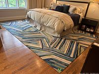 Full view of 9x12 rug under bed showing overall size, pattern, and colors