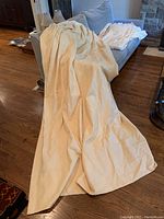 Two large, buttercream yellow curtain panels spread out on floor and sofa, showing fabric texture and size.