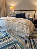 Full view of king bed with linen upholstered headboard, wood frame and bedding.