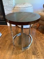 Side view of the round side table showing metal frame legs and dark wood top.