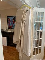 Photos show hanging and folded Williams-Sonoma 100% cotton table linens in white and cream colors, laundered and pressed.