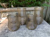 Four wire mesh lanterns placed on stone surface, showing two smaller and two larger lanterns in a group.