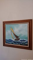 Full view of the framed nautical sailboat painting on wall showing natural wood frame and overall condition.
