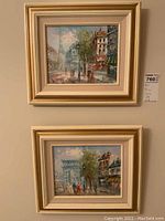 Two gold and cream framed oil paintings hung on a wall, showing Paris street scenes with people, buildings, and trees.
