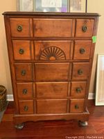 Front view of solid wood chest showing drawers, brass pulls, and carved decorative detail on middle drawer.