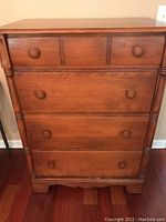 Front view of medium-brown solid wood vintage dresser with four drawers, round wooden knobs and decorative side columns