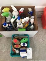 Another perspective of the box showing the variety of cleaning products and small basket with additional supplies inside the box.