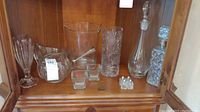 Photo of the collection inside a wood cabinet showing various glass vessels including ice bucket, pitchers, bottles, and vases.
