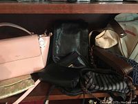 Photo showing handbags on a shelf including the pink Ralph Lauren handbag and various black and brown purses with floral and striped pouches