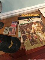 Overview photo showing all items including vinyl albums, four black 45 rpm records, and three cassette tapes including one Harry Chapin tape in case.
